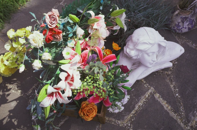 Composition florale déposée sur une sépulture avec statue commémorative